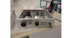 Electronic device chassis with components and wiring inside on a workbench.