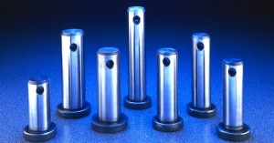 Five metallic cylindrical objects with holes, standing upright on a blue surface.