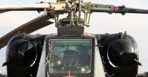 Close-up of a helicopter cockpit and mounted machine gun.