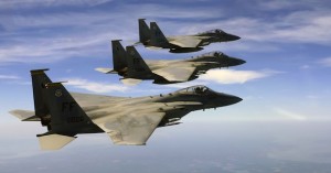 Four military fighter jets flying in formation against a blue sky.