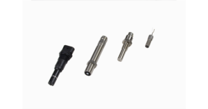 Four different metal and plastic industrial nozzles arranged in a row on white.