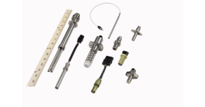 Various metal and plastic mechanical parts arranged with a ruler.