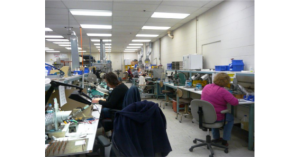 People working in a busy electronics assembly workshop.