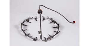 A metal animal trap with a circular design and a central trigger.