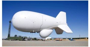 A large white blimp on the ground under a clear blue sky.