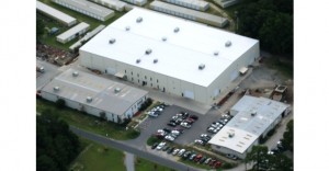 Aerial view of a large industrial warehouse with parked cars.
